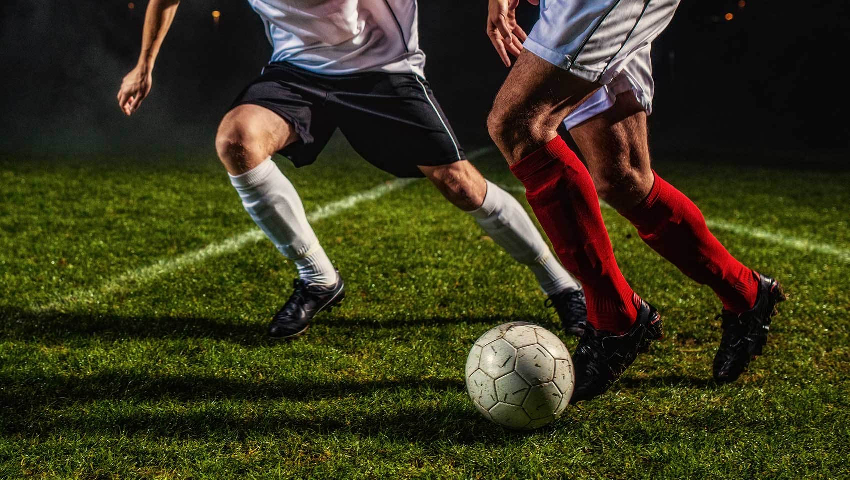 Two soccer players fight over ball on the field